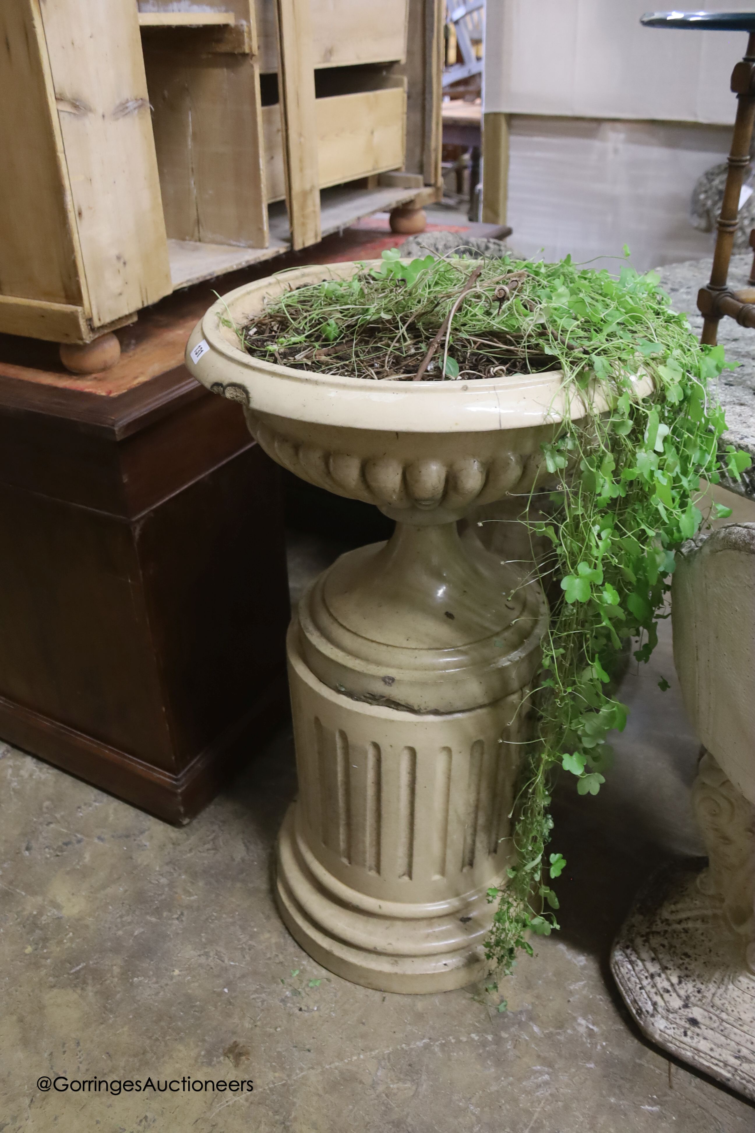 A buff-glazed stoneware garden urn on fluted pedestal